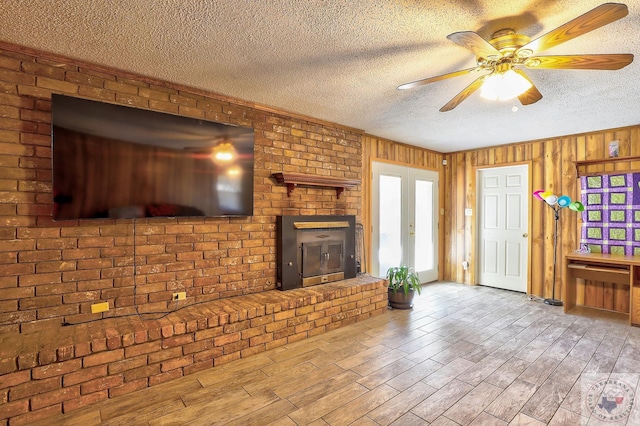 unfurnished living room featuring wooden walls, a textured ceiling, a fireplace, and wood finished floors