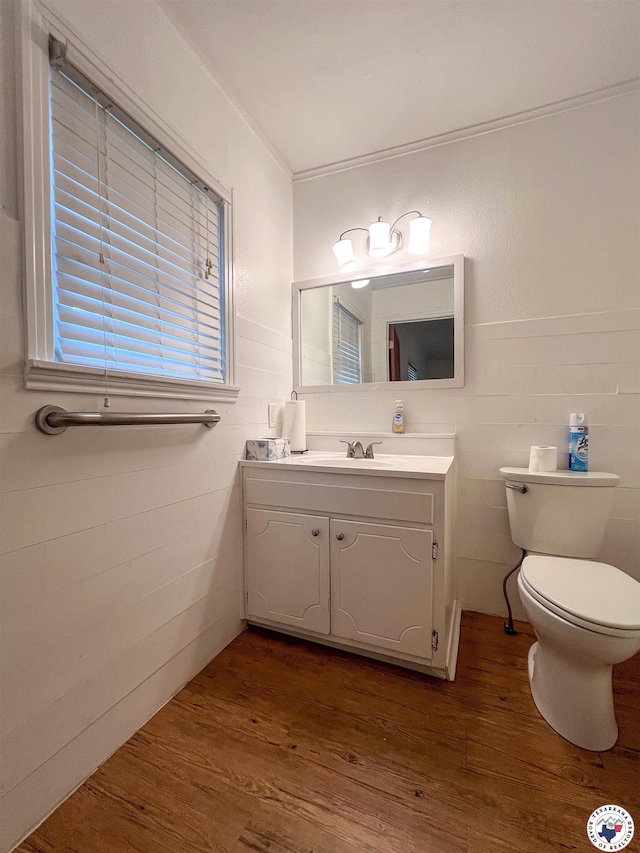 half bathroom with toilet, wood finished floors, and vanity