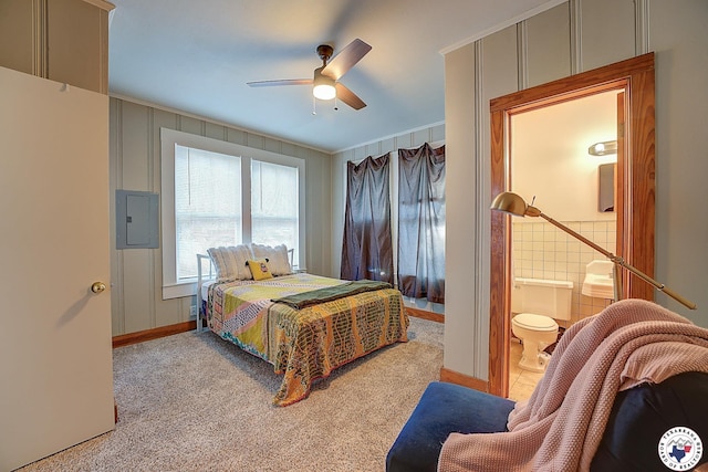 carpeted bedroom with crown molding, baseboards, ceiling fan, electric panel, and ensuite bath