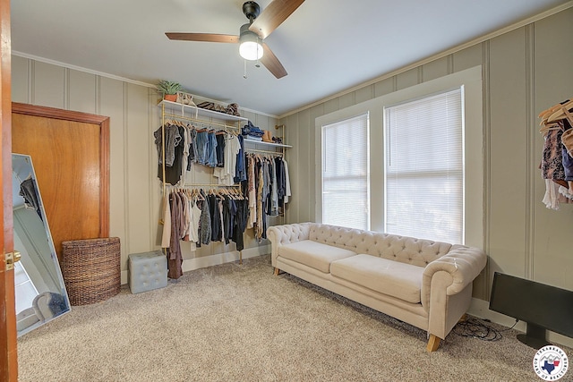 carpeted living room featuring crown molding, a ceiling fan, and a decorative wall