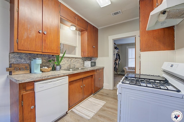 kitchen featuring brown cabinetry, white appliances, under cabinet range hood, a sink, and light wood-style flooring