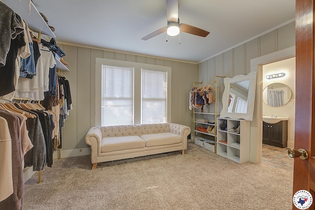 interior space with ornamental molding, carpet, a ceiling fan, and a decorative wall