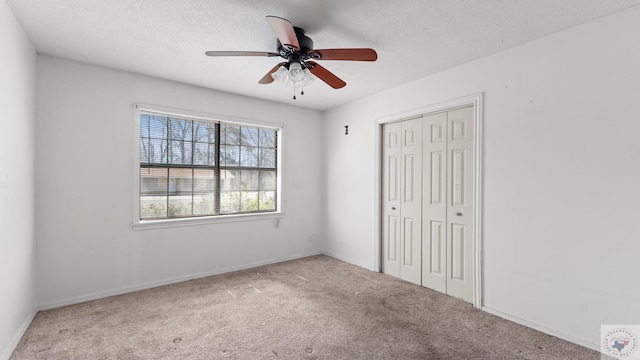 unfurnished bedroom with baseboards, ceiling fan, carpet flooring, a closet, and a textured ceiling