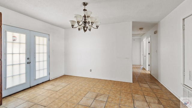 spare room featuring an inviting chandelier, light tile patterned floors, french doors, and baseboards