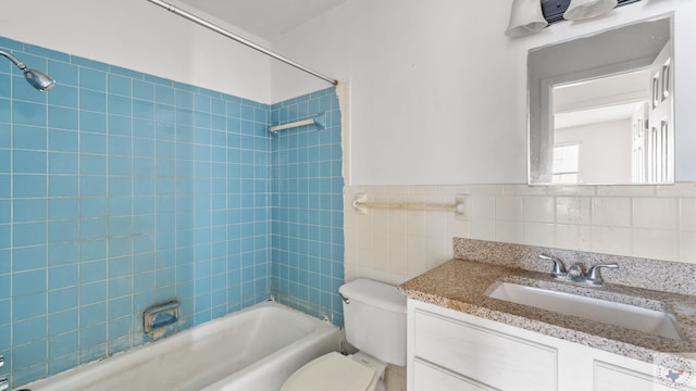 full bathroom featuring tile walls, a wainscoted wall, toilet, shower / bathing tub combination, and vanity