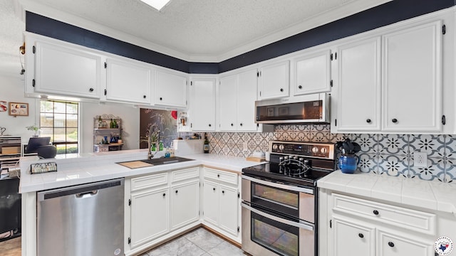 201 Larkspur Ln, Wake Village, TX 75501 - kitchen featuring stainless steel appliances, white cabinetry, a textured ceiling, a peninsula, and tile countertops