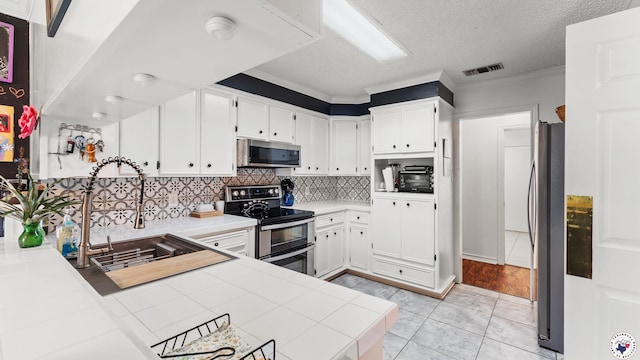 201 Larkspur Ln, Wake Village, TX 75501 - kitchen featuring appliances with stainless steel finishes, ornamental molding, backsplash, white cabinetry, and tile countertops