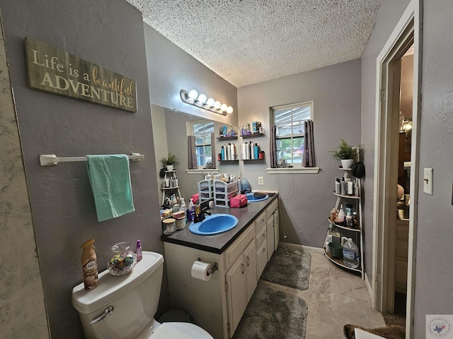 bathroom with vanity, toilet, and a textured ceiling