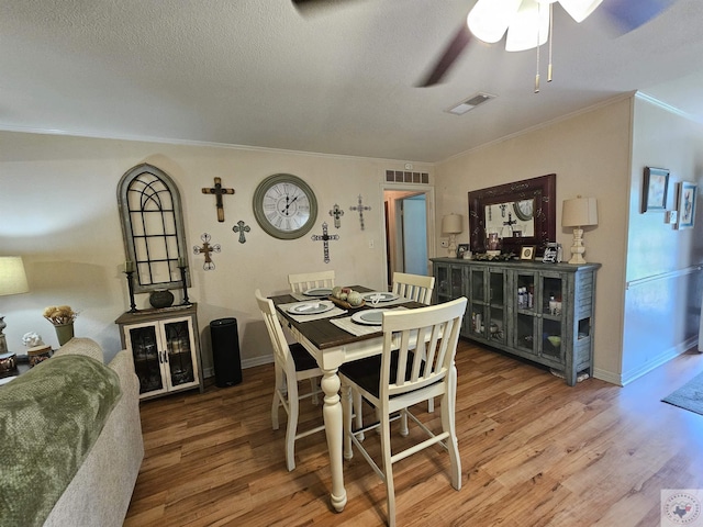 dining room featuring hardwood / wood-style flooring, a textured ceiling, crown molding, and ceiling fan