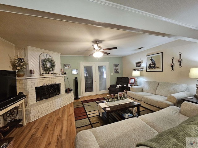 living room with a brick fireplace, wood-type flooring, crown molding, and french doors