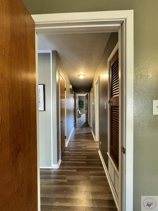 corridor featuring dark wood-type flooring and a textured ceiling