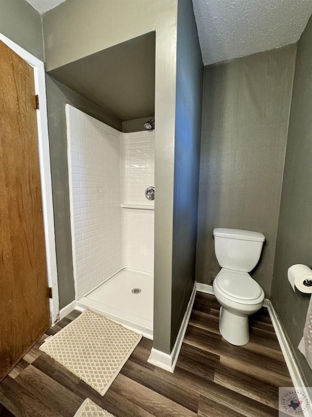 bathroom featuring wood-type flooring, toilet, walk in shower, and a textured ceiling