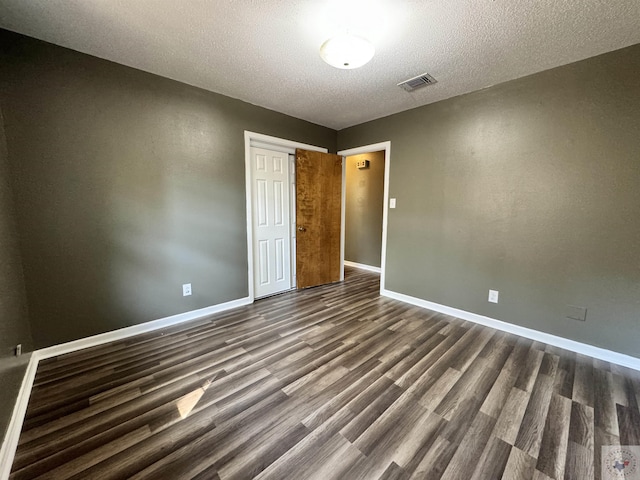 unfurnished bedroom with dark wood-type flooring, a textured ceiling, and a closet