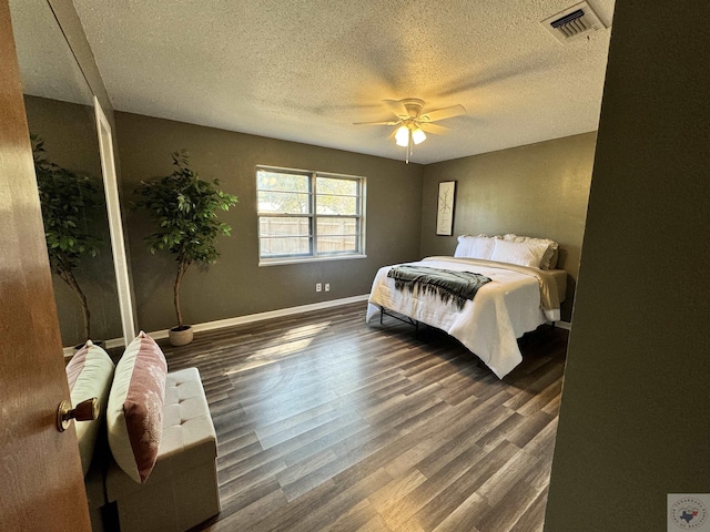 bedroom with a textured ceiling, dark hardwood / wood-style floors, and ceiling fan