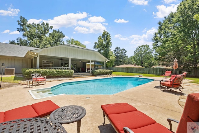 view of pool featuring ceiling fan, a patio area, cooling unit, and a diving board