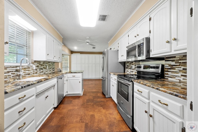 kitchen featuring dark stone counters, white cabinetry, appliances with stainless steel finishes, and decorative backsplash