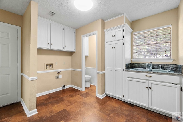 washroom featuring a textured ceiling, sink, hookup for a washing machine, hookup for an electric dryer, and cabinets