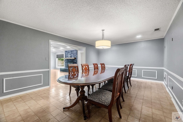 tiled dining space with a textured ceiling, a tile fireplace, and ornamental molding