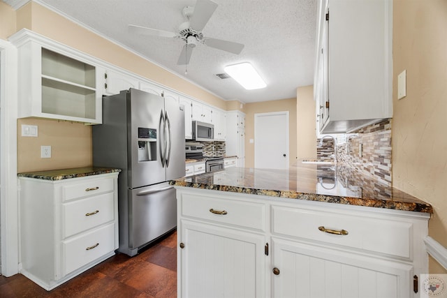 kitchen featuring sink, backsplash, white cabinetry, dark stone countertops, and stainless steel appliances