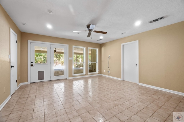 tiled empty room with ceiling fan and a textured ceiling