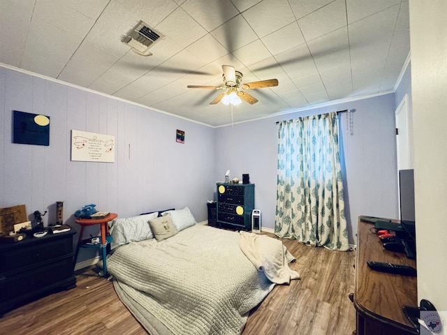 bedroom with ornamental molding, ceiling fan, and wood-type flooring