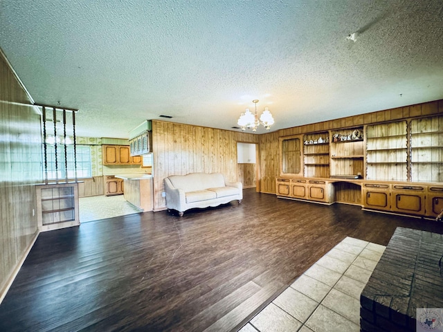 unfurnished living room with wood walls, an inviting chandelier, and wood-type flooring