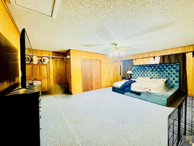 bedroom with carpet, wooden walls, a textured ceiling, and ceiling fan