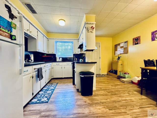 kitchen with light hardwood / wood-style flooring, white cabinets, white refrigerator, a center island, and sink