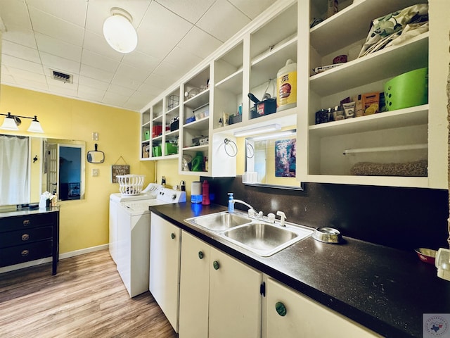 clothes washing area featuring cabinets, light hardwood / wood-style floors, washing machine and dryer, and sink