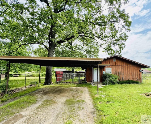 single story home with a front yard, a carport, and an outbuilding