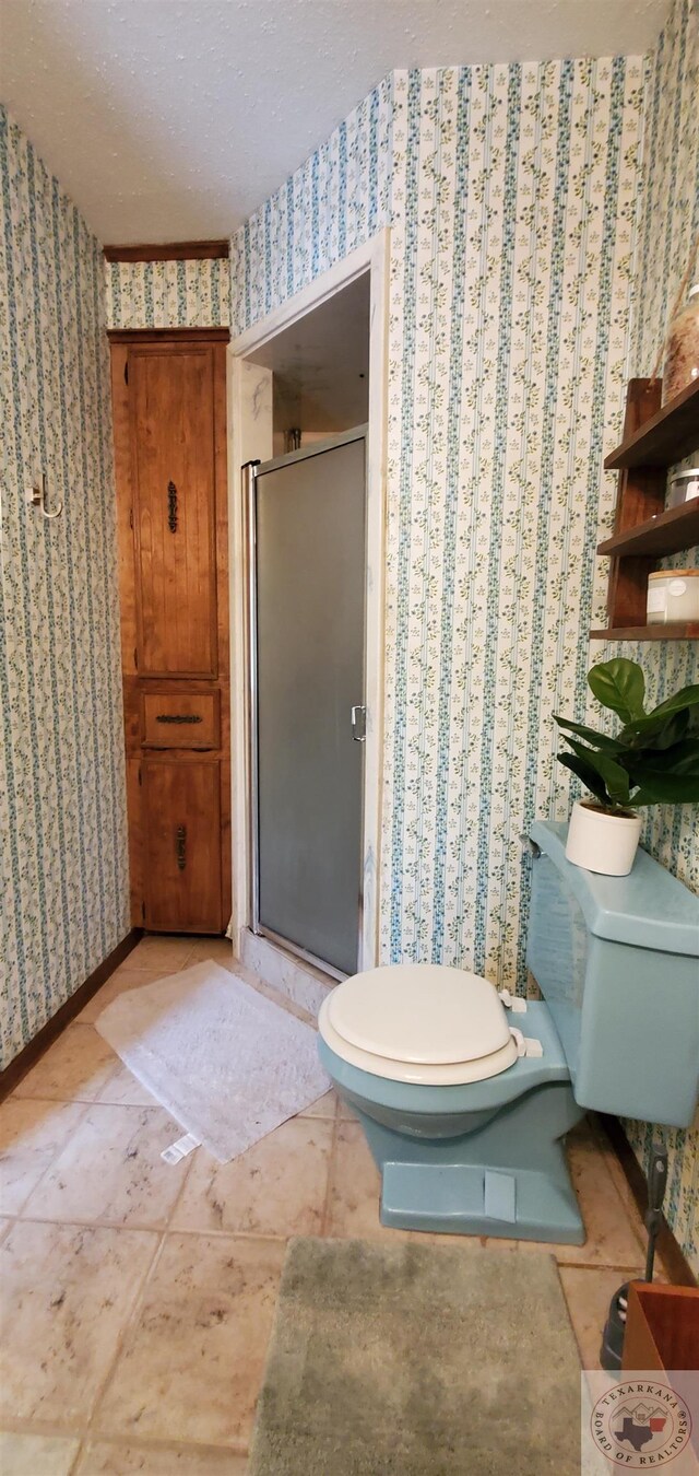 bathroom featuring a textured ceiling, toilet, tile patterned flooring, and walk in shower