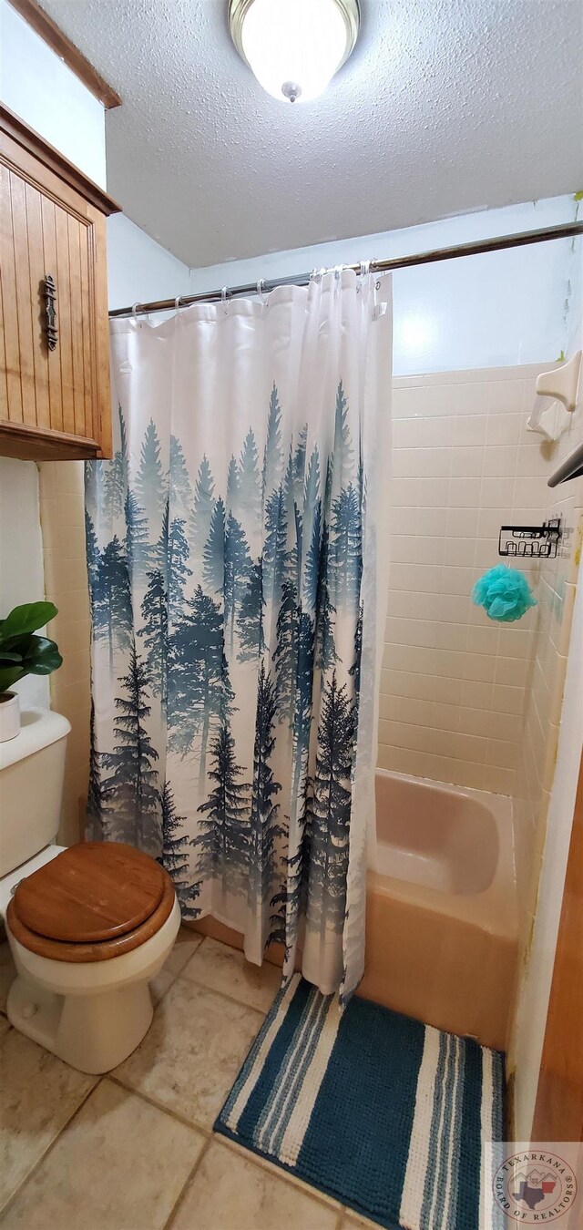 bathroom with a textured ceiling, shower / bath combo with shower curtain, and toilet