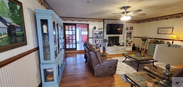 living room featuring a fireplace, wood-type flooring, and ceiling fan