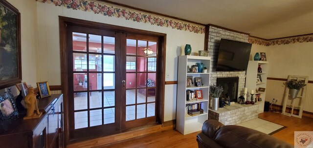 doorway to outside with a brick fireplace, hardwood / wood-style floors, and french doors