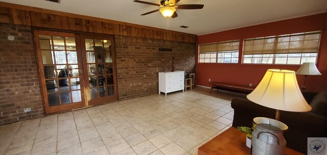 interior space with ceiling fan and brick wall