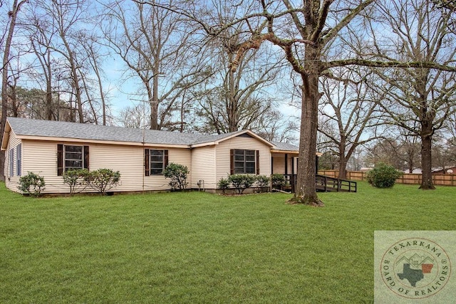 ranch-style home featuring a shingled roof, fence, and a front lawn