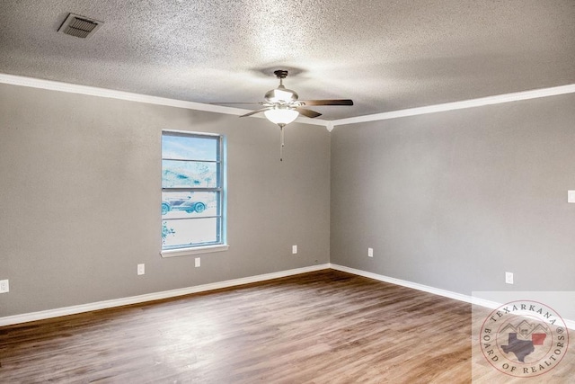 empty room featuring crown molding, visible vents, a ceiling fan, wood finished floors, and baseboards