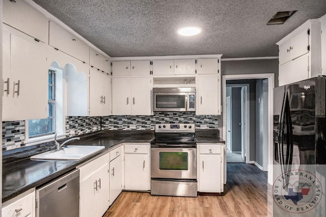 kitchen featuring dark countertops, white cabinetry, and stainless steel appliances