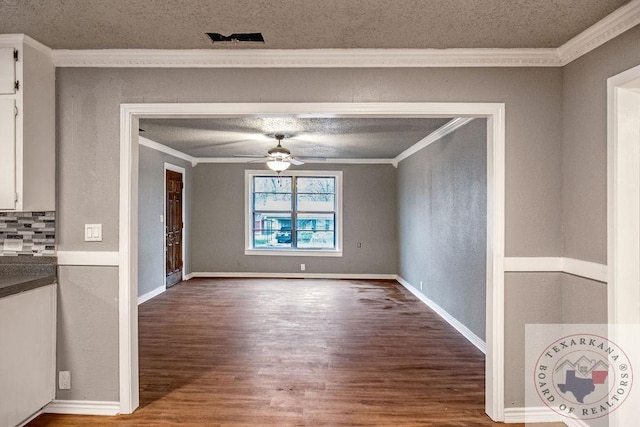unfurnished dining area featuring baseboards, a ceiling fan, ornamental molding, wood finished floors, and a textured ceiling