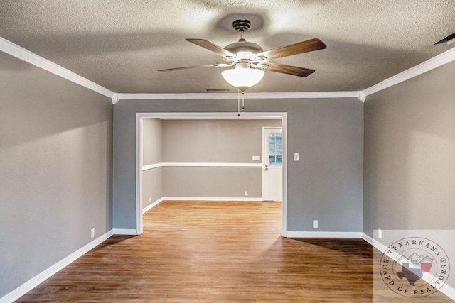 empty room featuring ornamental molding, a ceiling fan, baseboards, and wood finished floors