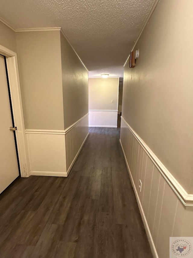 hallway featuring dark wood-type flooring, a textured ceiling, and crown molding