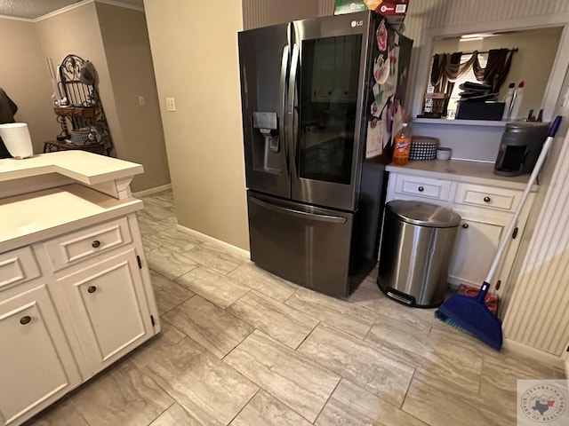 kitchen with white cabinetry, stainless steel refrigerator, and crown molding