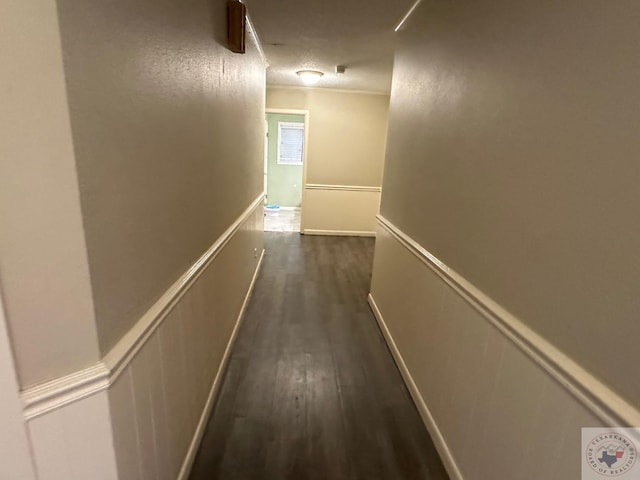 hallway with a textured ceiling, dark hardwood / wood-style floors, and crown molding