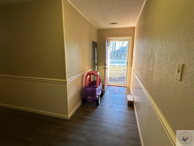 hallway with crown molding, a textured ceiling, and dark hardwood / wood-style flooring