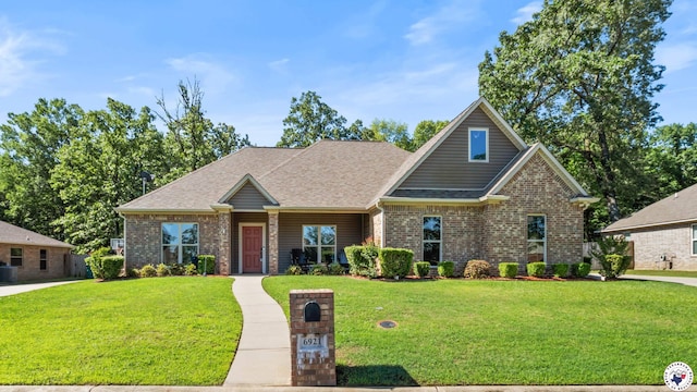 craftsman house with a front lawn, brick siding, and roof with shingles