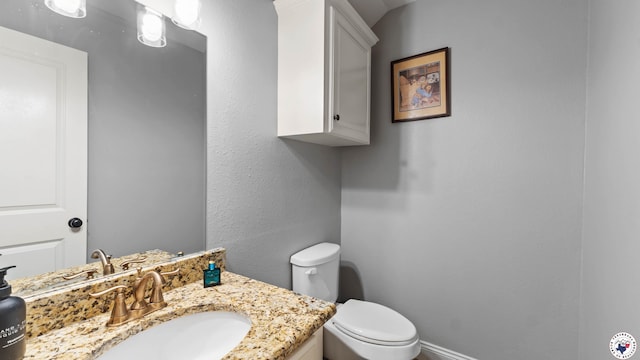 bathroom with vanity, toilet, and baseboards