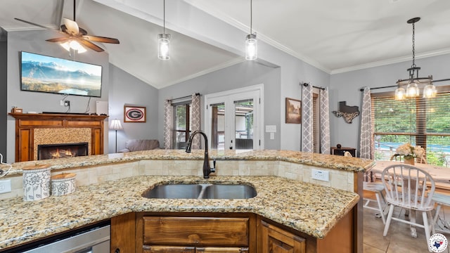 kitchen with brown cabinets, a tiled fireplace, pendant lighting, and a sink