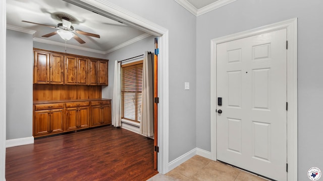 foyer entrance with crown molding, wood finished floors, baseboards, and ceiling fan