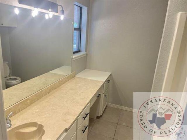 bathroom with toilet, tile patterned floors, and vanity