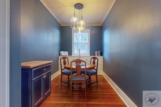 dining area with crown molding and dark wood-type flooring